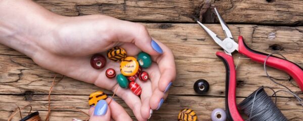 female hands with colored beads necklace manufacturing